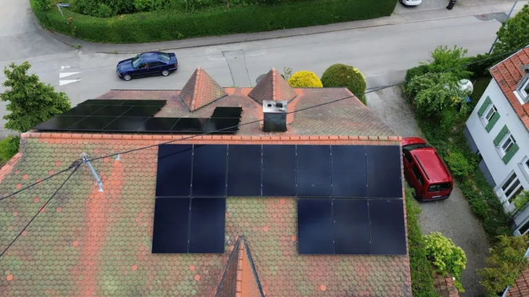 Drohnenaufnahme einer Photovoltaikanlage mit schwarzen Modulen auf einem roten Ziegeldach