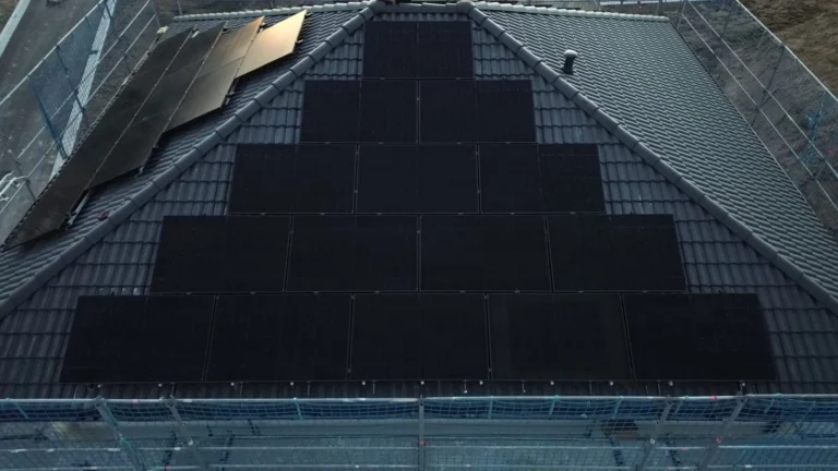 Schwarze Solarmodule auf einem dunklen Dach, das Gerüst steht noch