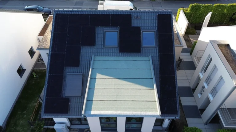 Luftaufnahme: modernes Wohnhaus mit schwarzen Solarmodulen rund um das Glasdach